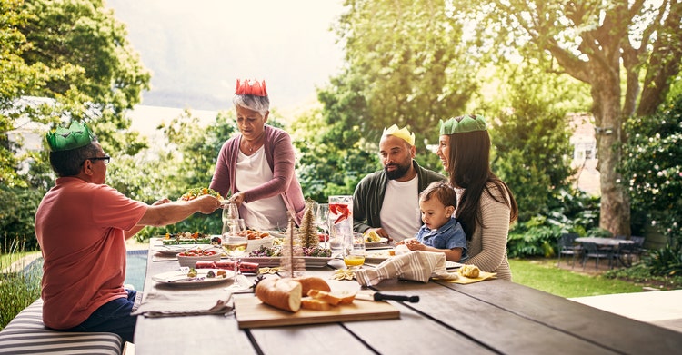 Family lunch outdoors on a picnic table with party hats