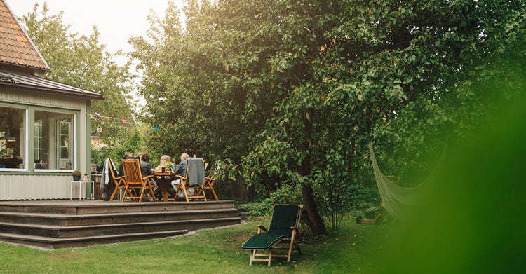 Family eating outside on the house porch surrounded by trees