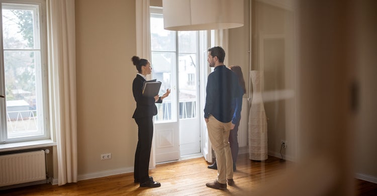 Professional woman standing with a couple in a new home